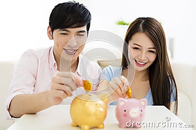 Happy couple putting coin into piggy bank Stock Photo