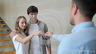 Happy couple receiving apartment key from real estate agent. Happy couple smiling and getting keys from new real estate Stock Photo