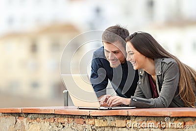 Happy couple searching online content on a laptop Stock Photo