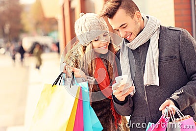 Happy couple shopping in the city with smartphone Stock Photo