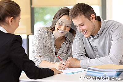 Happy couple signing a contract at office Stock Photo