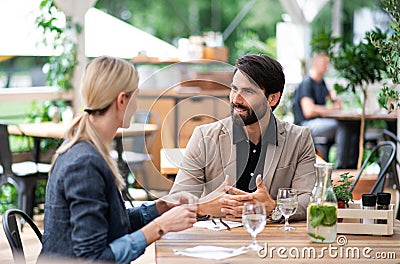 Happy couple sitting outdoors on terrace restaurant, talking. Stock Photo