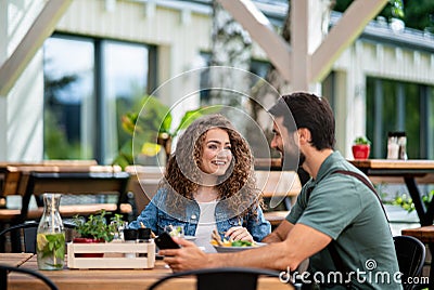 Happy couple sitting outdoors on terrace restaurant, talking. Stock Photo