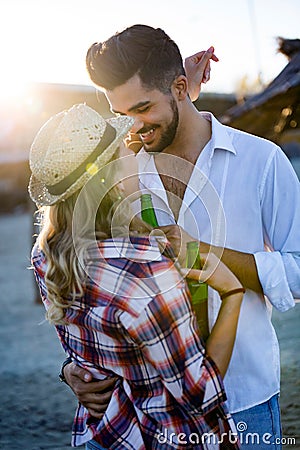 Happy couple smiling and drinking beer at beach Stock Photo