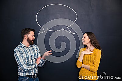 Happy couple talking over chalkboard background with drawn dialogue Stock Photo