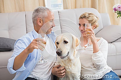 Happy couple with their pet dog drinking champagne Stock Photo