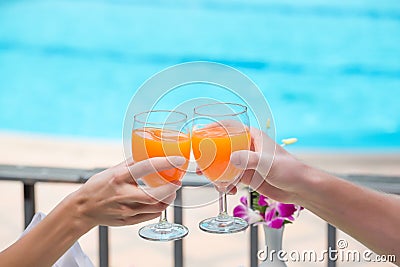 Happy couple with two glasses of orange juice at swiming pool vacation Stock Photo