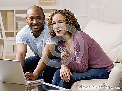 Happy couple using credit card to shop online Stock Photo