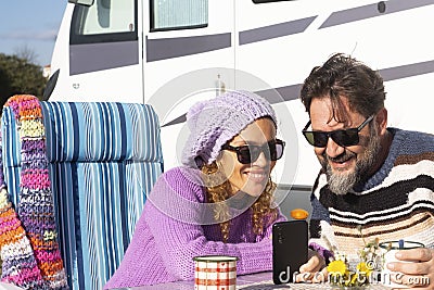 Happy couple of van camper tourist traveler enjoy time together using mobile phone to plan road trip and next destination. People Stock Photo