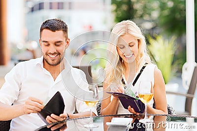 Happy couple with wallet paying bill at restaurant Stock Photo