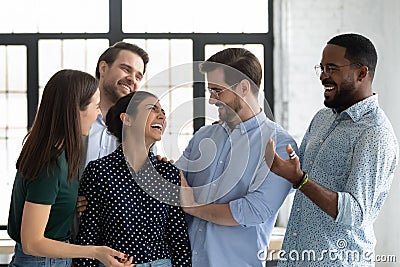Happy coworkers congratulating excited Indian female employee Stock Photo