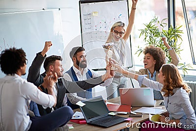 Happy coworkers holding a throphy, excited for their busines achievements. Celebrating company success Stock Photo