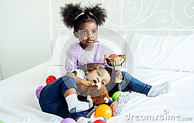 Happy cute active little african american kids boy and girl relaxing on bed at home Stock Photo