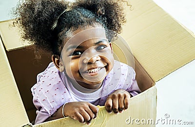 Happy cute active little african american kids girl play riding in cardboard boxes feel excited to move in new house Stock Photo
