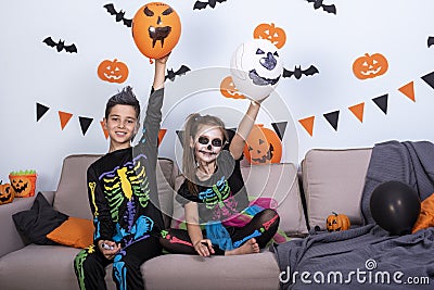 Happy cute children boy and girls in costume on sofa in living room during Halloween party. Stock Photo