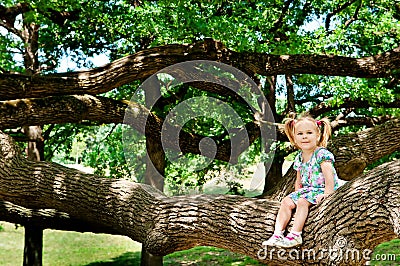 Happy cute girl sitting on branch huge tree Stock Photo