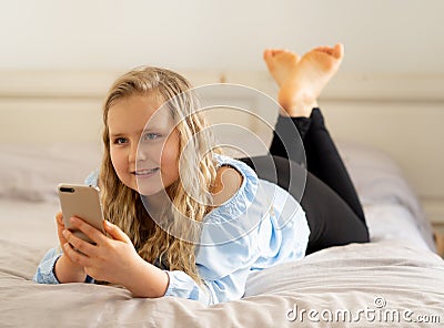 Happy cute kid playing games and watching videos on social media on mobile phone Stock Photo