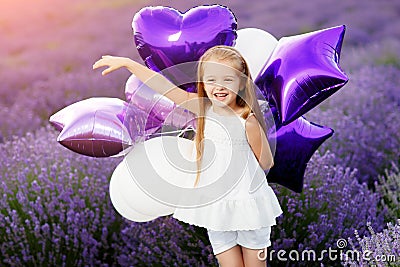 Happy cute little girl in lavender field with purple balloons. Freedom concept. Stock Photo