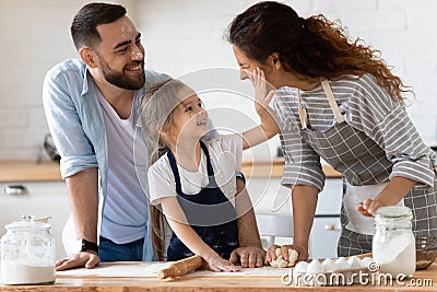 Happy cute little preschool girl spreading flour on cheerful parents. Stock Photo