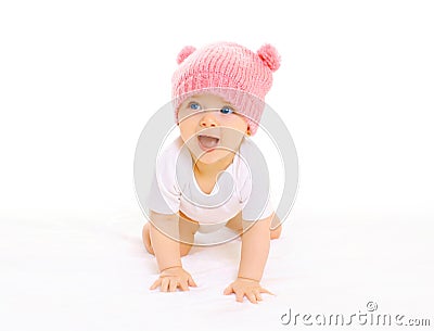 Happy cute smiling baby in knitted pink hat crawls on a white Stock Photo