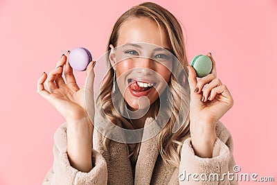 Happy cute young pretty woman posing isolated over pink wall background holding cake macaroons sweeties Stock Photo