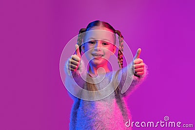 Happy cutie preteen girl showing thumb ups on colorful background Stock Photo