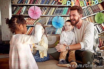 A happy Dad enjoying a kids birthday party at home with his biological and adopted kids. Family, celebration, together Stock Photo