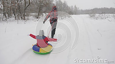 Happy dad sledges a child on a snowy road. Christmas Holidays. father plays with his daughter in a winter park. The Stock Photo