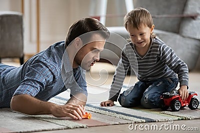 Happy dad and son wheeling toy cars on heat floor Stock Photo