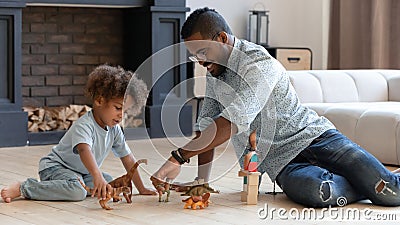 Happy daddy and toddler son playing games with small dinosaurs Stock Photo