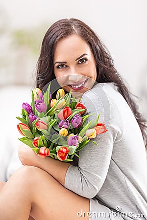 Happy dark haired woman holding a lovely bouquet full of tulips during national womenâ€™s day Stock Photo