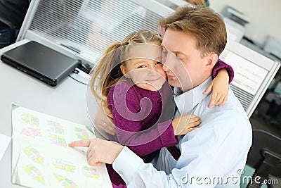 Happy daughter hugs her father who views apartment plan booklet Stock Photo