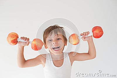 Happy delightful active strong small laughing kid in tank top lifting dumbbells made from apple fruits easy during workout Stock Photo