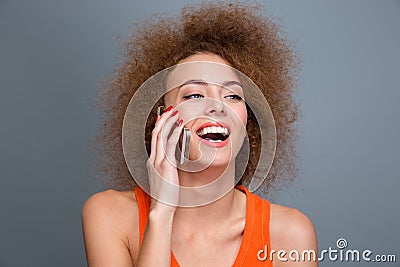 Happy delightful curly woman talking on mobile phone and laughing Stock Photo