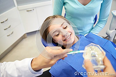 Happy dentist showing toothbrush to patient girl Stock Photo