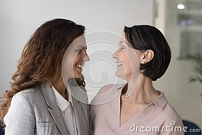 Happy different age colleagues, teammates laughing hugging standing at workplace Stock Photo