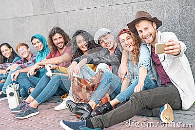 Happy diverse friends taking selfie with mobile smart phone camera - Millennial young people having fun making photos Stock Photo