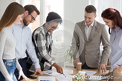 Happy diverse team brainstorm in office with papers on table Stock Photo