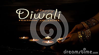 Happy Diwali - Woman hands with henna holding lit candle isolated on dark background Stock Photo