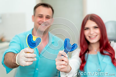 Happy doctor dentist with his patient show the result of impressions of her teeth on a spoon with silicone material Stock Photo