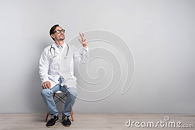 Happy doctor in smock sitting on a chair Stock Photo