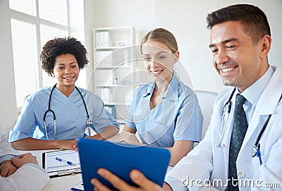 Happy doctors with tablet pc meeting at hospital Stock Photo