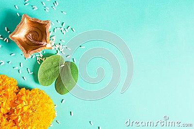 Happy Dussehra. Clay Diya lamps lit during Dussehra with yellow flowers, green leaf and rice on green pastel background. Dussehra Stock Photo