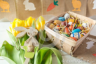 Happy Easter! Box with colorful eggs on white wooden table. Close up eggs, tulips, bunny. Decoration for Easter Stock Photo