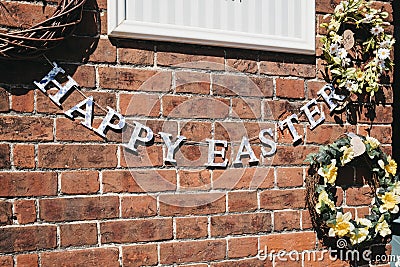 Happy Easter bunting against brick wall outside a shop in Sheringham, Norfolk, UK Editorial Stock Photo