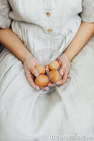 Happy Easter! Easter eggs in hands of woman in rustic linen dress. Aesthetic eco holiday Stock Photo