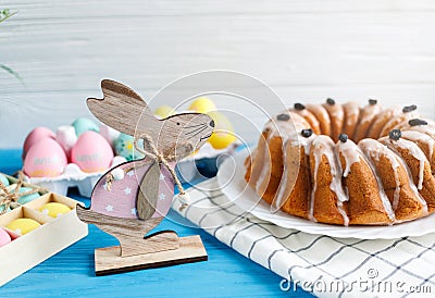 Happy Easter! Handmade cake on towel, eggs, wooden bunny rabbit on blue wooden background. Decoration for Easter Stock Photo