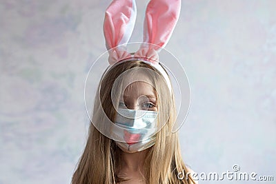 happy Easter. A littel girl with long blonde hair in rabbit ears. She is wearing a medical mask painted with a muzzle Stock Photo