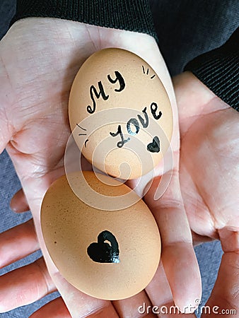 Happy Easter or st valentines morning before breakfast. Young couple holding eggs with declaration of love. Art on eggs Stock Photo