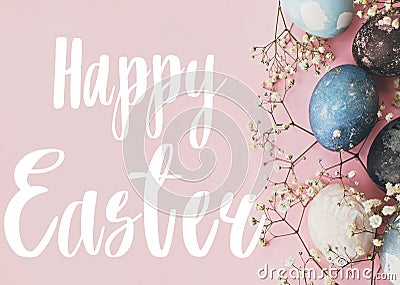 Happy Easter text. Easter greetings card. Stylish easter eggs and spring flowers border on pink paper flat lay. Modern natural Stock Photo